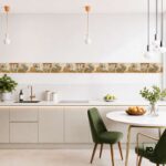 Modern kitchen with cream cabinets, patterned backsplash, and brass faucet; green upholstered dining chairs and round marble table with fruit bowl.