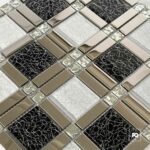 Malla decorativa echo de vidrio negro y blanco 30 x 30 cm-tiles-2-ok | Plomería García Close-up of a decorative tiled surface with interlocking beige metal tiles and black cracked-glass panels in a geometric grid.