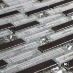 Close-up of a circuit board with black rectangular chips mounted on a silver grid of interconnections.