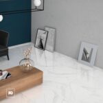Modern living room corner with blue wall, marble floor, wooden coffee table, and a glass vase with dried branches.
