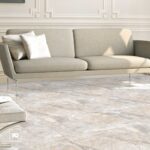 Xrddaft5nfpyno369j8334319821278606497t23111000 | Plomería García Modern beige sofa with white pillows in a bright, elegant living room featuring decorative wall paneling and marble floor tiles.