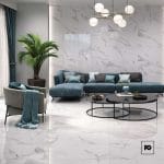 Modern living room with white marble walls and floor, a teal sectional, gray chair, large plant, and circular coffee tables.