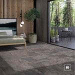 Modern bedroom with wooden slat wall, low bed, and potted tree beside a large glass sliding door opening to a patio with outdoor table and plants.