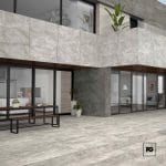 Modern stone-clad building with large glass doors, outdoor picnic table, and potted plants.