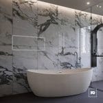 Modern bathroom with a white freestanding tub, marble tile walls, and a glass shower enclosure.