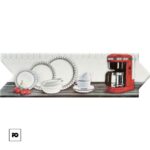 Red coffee maker sits on a wooden counter beside white dishes, cups, and a small bunch of cherries, against a light tiled background on a kitchen counter banner.