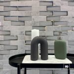 Malla decorativa de vidrio y mármol holly 30 x 30 cm-tiles-2-ok | Plomería García Decorative bathroom vignette on a round black tray: white candle, black u-shaped sculpture, and green soap dispenser on a marble-topped surface.