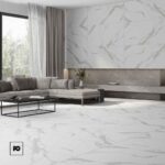 Piso porcelánico tipo mármol blanco mate colossale 80 × 160 cm-tendenzza-2-ok | Plomería García Modern living room with white marble floors and walls, a gray sectional sofa, and a black metal coffee table with a low profile.