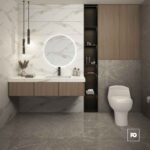 Modern bathroom with a round backlit mirror, white sink on a floating wood vanity, dark open shelving, tall cabinet, and a white toilet amid gray marble tiles.